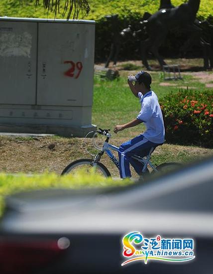 6月4日，一学生双手不扶车龙头骑行在三亚凤凰路上。(三亚新闻网记者沙晓峰摄)