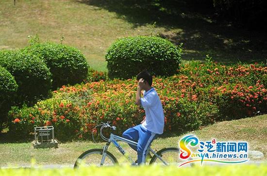 6月4日,一学生双手不扶车龙头骑行在三亚凤凰路上。(三亚新闻网记者沙晓峰摄)