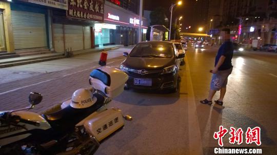 6月4日晚,南宁青林路一辆私家车被协警“贴单”,其前后是开来吃宵夜的警车。王刚 摄