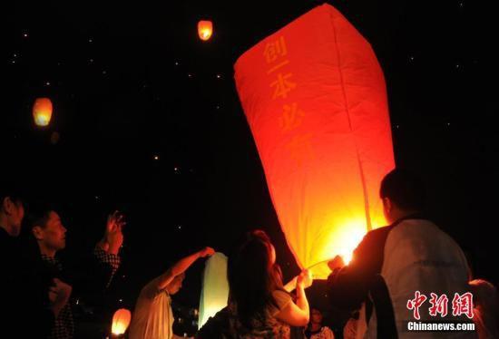 6月4日,赶考前夜,毛坦厂中学的学生们在孔明灯上写下心愿,向天空放飞希望,万只孔明灯映红了小镇上空。当日,安徽省六安市毛坦厂镇毛坦厂中学即将迎来2015年度高考。赶考前夜,高三学生与陪读家长在学校周边的空地上放飞孔明灯,预祝高考金榜题名。 中新社发 韩苏原 摄