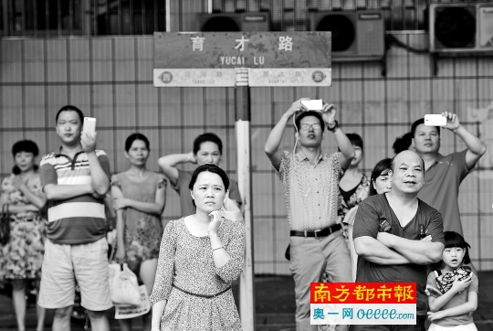 昨日上午,东莞南城中学,语文考试结束,大批家长站在考场门口拍摄考生走出校门的时刻。