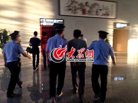 辦案民警押著犯罪嫌疑人趙某國走向菏澤火車站客運值班室