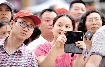 一名守在考点外的家长举着手机准备拍摄孩子走出考场瞬间