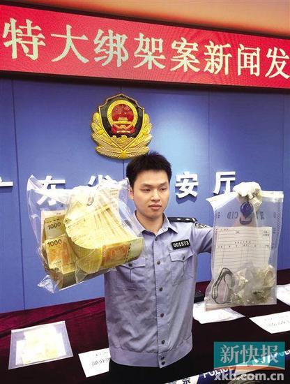 ■5月14日,民警在新闻发布会上展示缴获的涉案赎金和赃物。新华社发