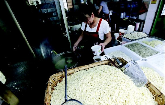昨日，戶部巷一家面館的店主正在為顧客煮熱干面。本報記者 傅堅 攝