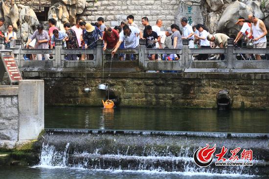 6月13日，济南持续高温天气，黑虎泉畔打水的市民排起了长队。记者看到，东侧两只虎头喷涌量极小，正下方被激起白色水花的泉池十分平静。