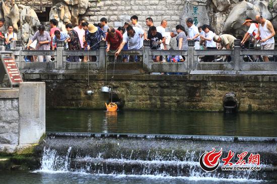 6月13日,济南持续高温天气,黑虎泉畔打水的市民排起了长队。记者看到,东侧两只虎头喷涌量极小,正下方被激起白色水花的泉池十分平静。