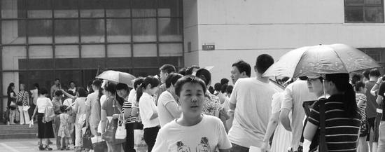 一位已經(jīng)報完名的孩子走出報名點，他的身后是長長的隊伍