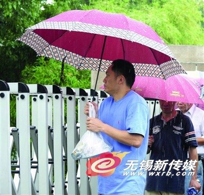 昨天中午,一位买好快餐的家长在大雨中等候中考的孩子。