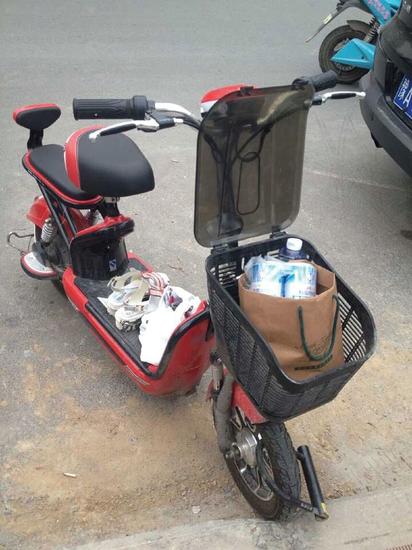 電動車車簍里放著沒打開的啤酒，腳踏板上有一雙女式涼鞋