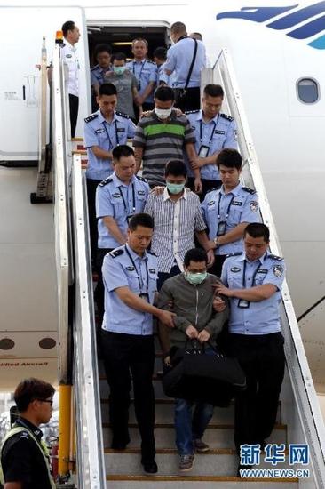 6月21日,公安人员在北京首都机场押解经济犯罪嫌疑人走下飞机。 (来自:新华网)