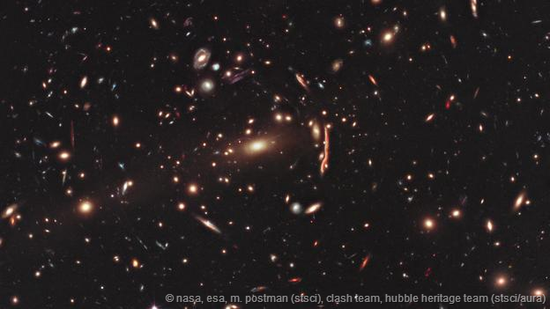 哈勃空间望远镜拍摄的图像。大质量天体会造成背景星系光线的弯曲，这是爱因斯坦的理论所预言的情景，被称作“引力透镜”
