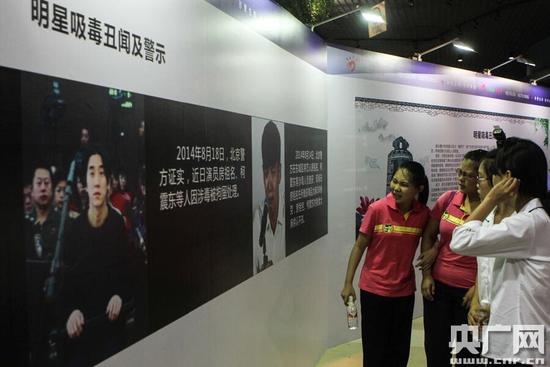 在明星吸毒丑闻及警示展板前,中学生驻足观看。(央广网记者 张垒 摄)