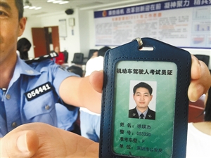 昨日,市车管所,民警向记者展示有轨电车考官证件.