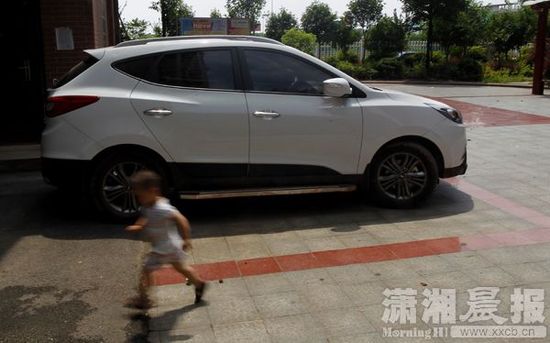 6月28日，湘潭某小区，出事的车子还停在小区里，一小朋友从车子边跑过。图/潇湘晨报记者 华剑