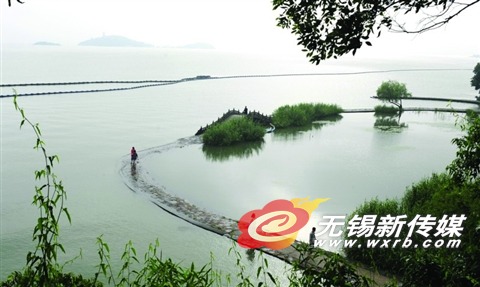 这是6月28日,游人经过部分被水没过的鼋头渚万浪桥堤岸。 (还月亮 摄)