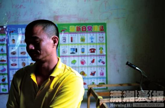 7月1日，江锋坐在客厅里，身后是6岁儿子小嘉认字的挂图，他说不怪妻子李玲，“她这么做是压力太大了。”图/记者陈勇