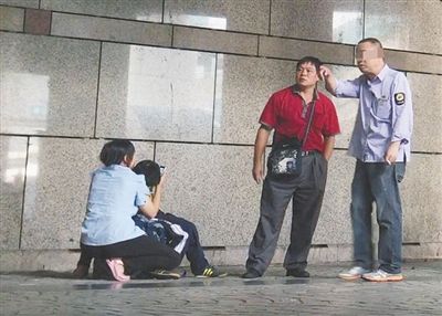7月4日,北京西站A1出口外,身着“公交集团制服”的医托与来京患者家属搭话。女家属蹲在地上,抱着生病的孩子。