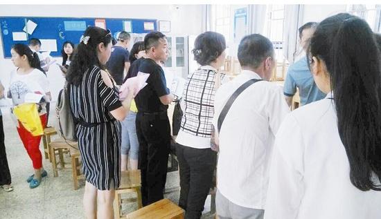 图为:一所民办初中教室内,家长排队登记
