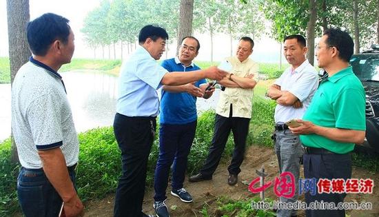河南遂平廣源飼料科技有限公司董事長趙遵喜（左二）向河南省農業綜合開發公司考察組負責人一行介紹環境治理情況