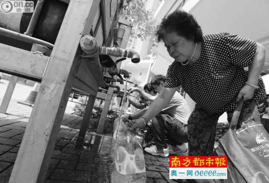居民携水瓶前往水车领取饮用水。