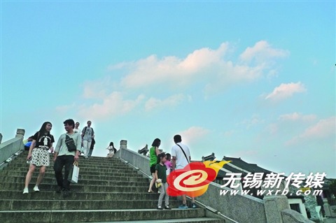 黄昏时分,南长街景区跨塘古桥上看天赏云的游人。