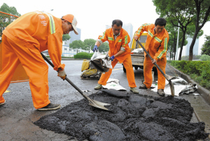 昨天,鄞州区市政工作人员在鄞县大道中段用防水沥青修补道路。