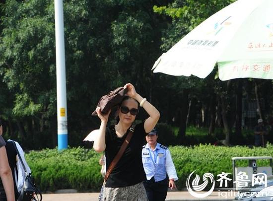 昨天上午十时许,市民用手提包遮挡烈阳,匆匆穿过马路。