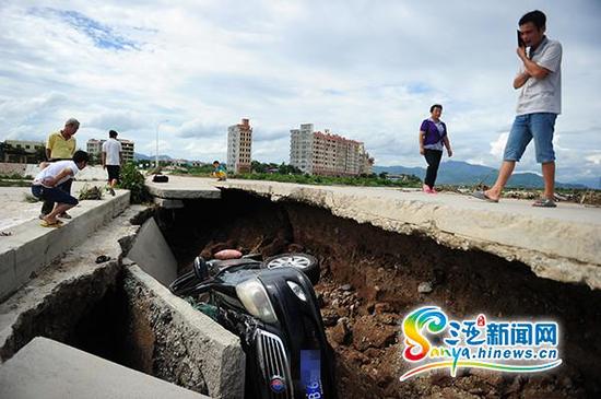 7月21日,水中桥桥面塌陷“吞噬”一辆汽车引路人围观。(三亚新闻网记者沙晓峰摄)