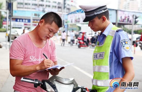 2015年7月22日,海口市龙昆南路,协警对不遵守交通规则行驶的车主进行教育。(海报集团全媒体中心记者张茂摄)