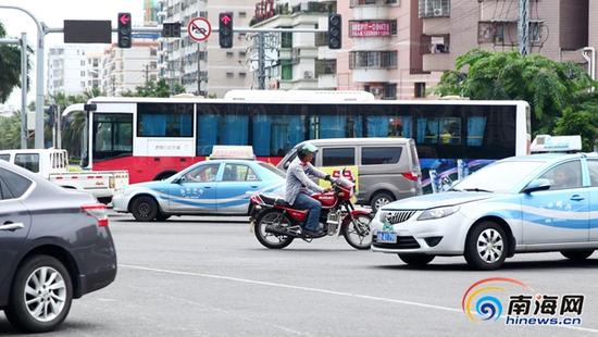 015年7月22日,海口市龙昆南路,一辆闯红灯逆行行驶的摩的在车流中,十分危险”。(海报集团全媒体中心记者张茂摄)