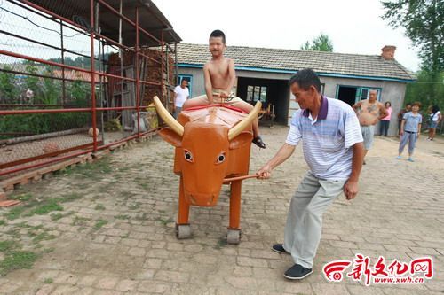 电动牛驮着小孩走来走去 新文化报 王强 摄