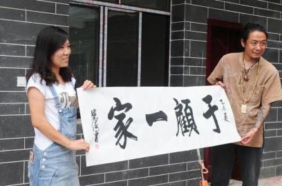 顾少强和于夫向记者展示朋友赠送的写了客栈名字的条幅。