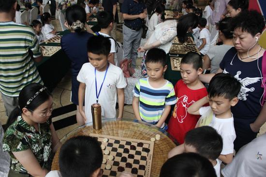 图三：亚洲冠军阿拉腾花与小营员的指导棋吸引众多爱好者驻足观看