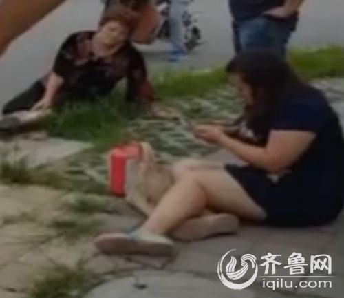 紅色轎車里的母女兩人傷勢嚴重,被人扶到路邊之后,臉上表情非常痛苦。(視頻截圖)