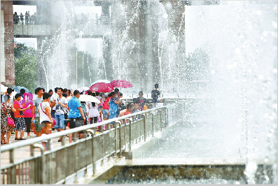昨日，众多游人与市民在泉城广场的喷泉边亲水纳凉。当日，济南气温再创新高。(本报记者 范良 摄)