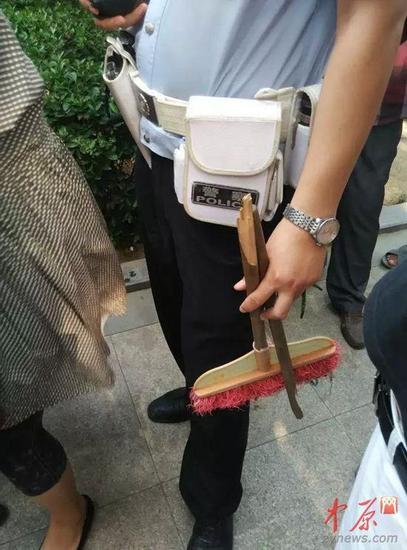 民警手中正是老太打人的掃帚。