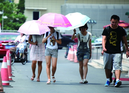 昨日在省城街頭,出行的市民打傘遮蔽烈日 記者王曉峰攝