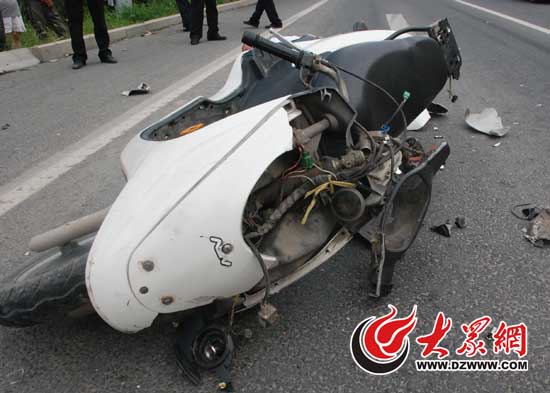 白色摩托车倒地并严重损毁，骑车人当场死亡。
