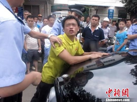 图为案发当天现场,男子趴在车头不肯离去 王贤哲 摄