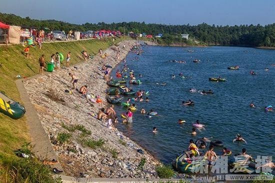 8月2日，宁乡县白马桥水库，许多市民前来游泳，河堤上停满了私家车、摩托车以及售卖泳衣、泳圈的摊贩。图/潇湘晨报记者张迪