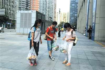 7月31日，殷亚东（中）和同伴从超市购买了40瓶饮料，准备作为礼物送给扫二维码的市民。每成功扫码一单，他们可从微商处拿到5元提成。