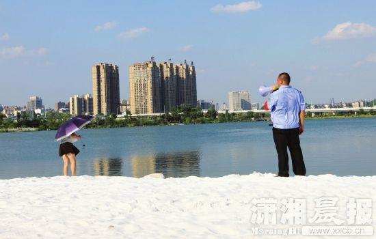 月3日，长沙梅溪湖白沙滩，保安拿着喇叭劝说下水游泳的市民上岸。