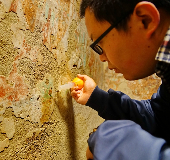 针对起甲的壁画，壁画修复师采用注射黏结剂的方法增加颜料层与地仗层的黏结力 谢震霖 图