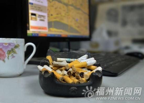 某家单位,员工下班离去,办公桌上留下一烟灰缸的烟头