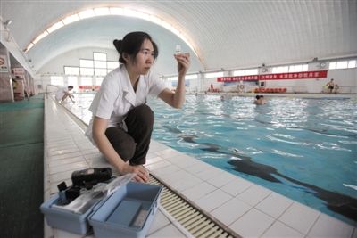 7月15日，首钢篮球中心游泳馆，工作人员在取泳池内的水样准备检测。本版摄影/新京报记者 薛珺