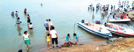 8月4日下午，郑州市花园口黄河南岸沿线，大批冒险在黄河内戏水消暑的市民