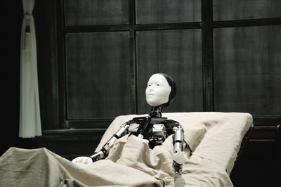 《变形记》中饰演儿子“格里高尔”的机器人Repliee S1有着白色的面孔和金属的身躯，全剧过程中都坐在床上，动作不多，但表情十足抢戏。
