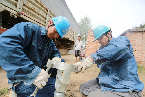 職工頂烈日酷暑加緊絕緣導(dǎo)線架設(shè)和電桿移除作業(yè)