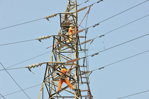 年近五旬的電力師傅在熱的像烙鐵的鐵塔上檢修